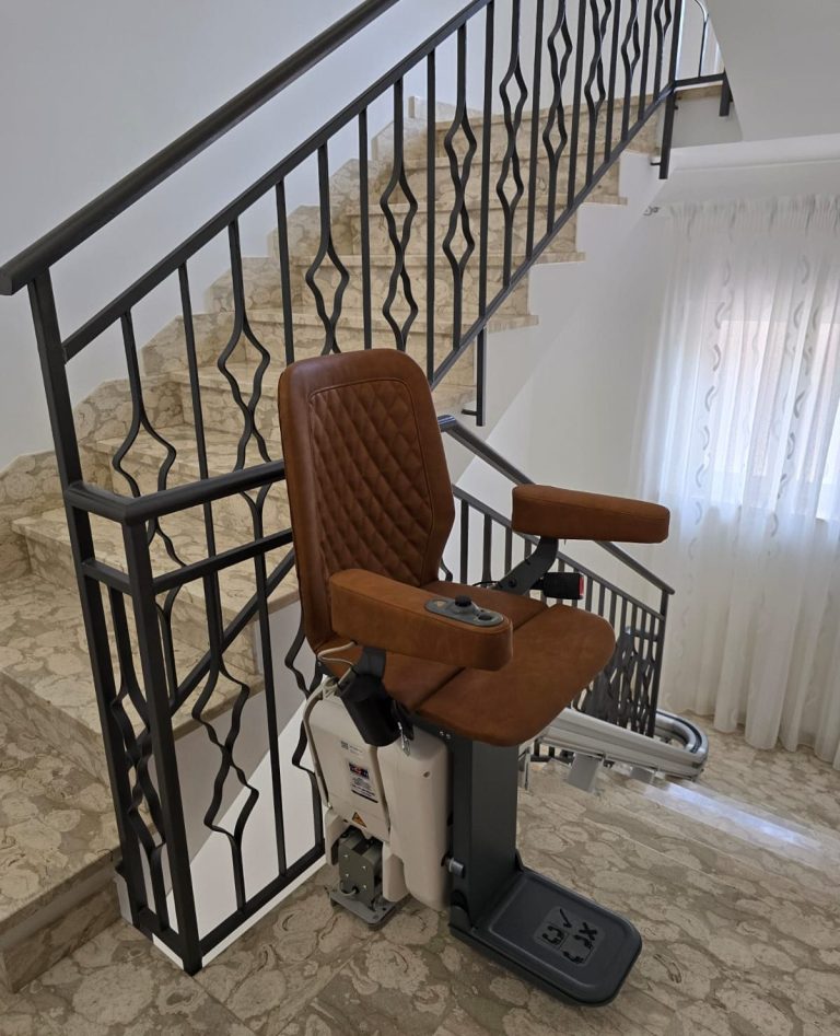 Treppenlift mit braunem Sitz an einer Treppe, leichte Wandverkleidung im Hintergrund in Warendorf