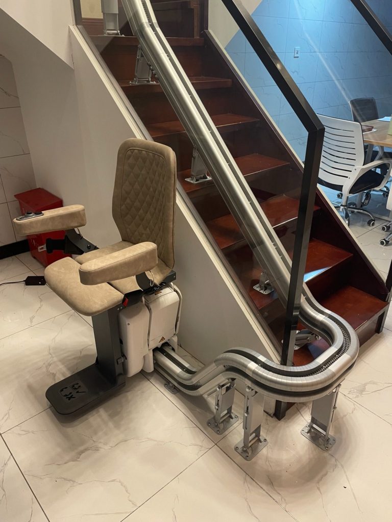 Treppenlift mit gepolsterter Sitzfläche am Fuße einer Treppe.