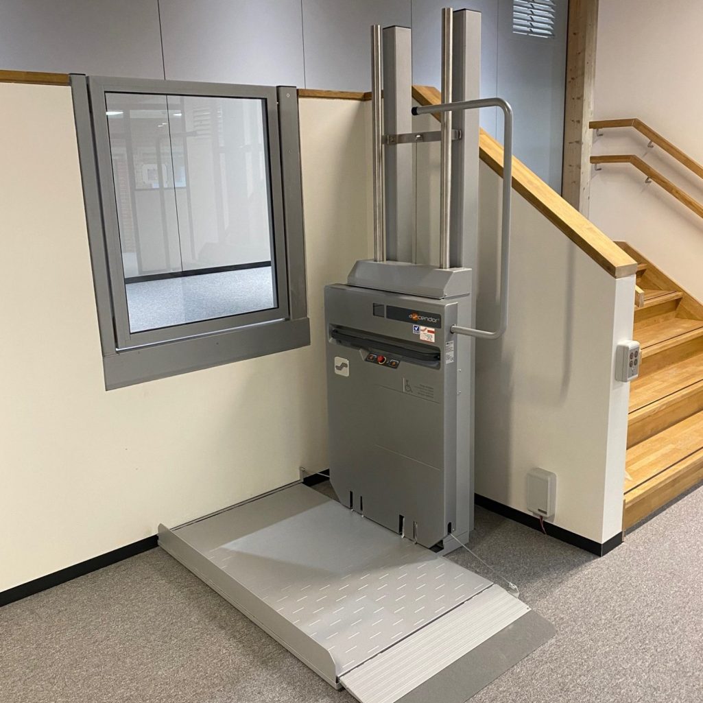 Rollstuhlrampe neben einer Treppe mit einem Fenster in der Wand.